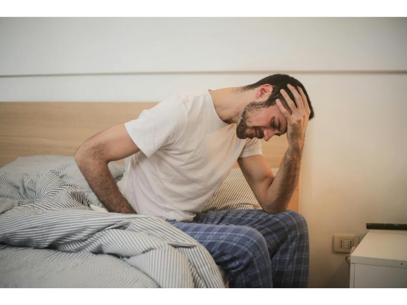 loan fatigue image of man holding his head sitting on bed